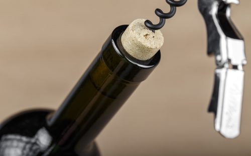 bottle of wine with a corkscrew in a cork, closeup. start of a celebration or romantic evening