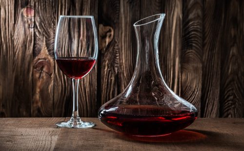 decanter and glass with red wine on vintage wooden background