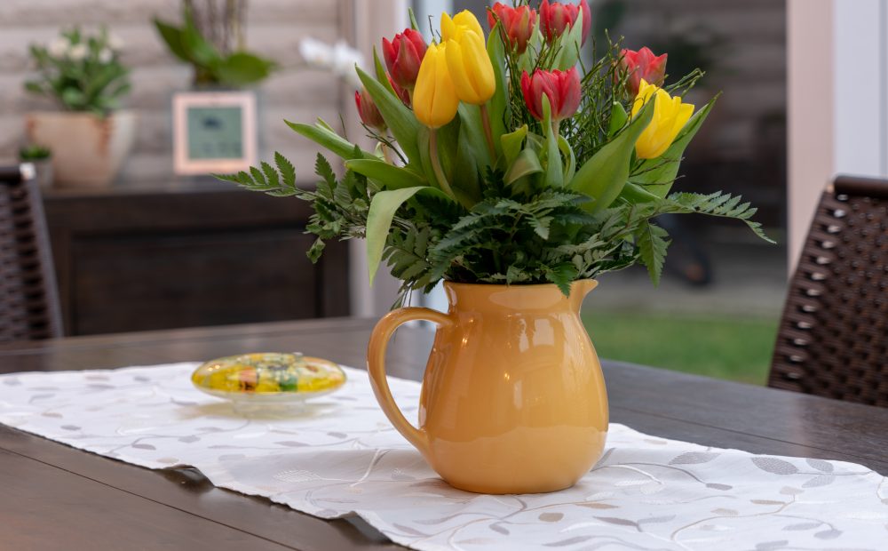 a bouquet of colourful tulips stands in a yellow vase