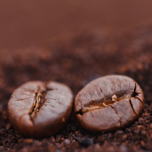 Coffee beans on ground coffee background