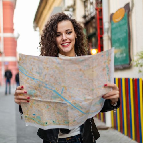 Cheerful woman searching direction on location map while traveling abroad. People travel concept